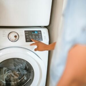 Hand selecting laundry options on a digital washing machine control panel indoors.