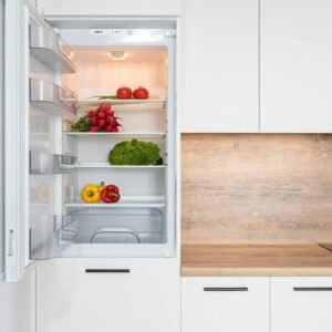 Open fridge in a sleek kitchen with fresh vegetables, perfect for healthy meals.