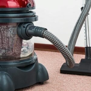 Close-up of a modern vacuum cleaner with water filtration on carpet floor indoors.